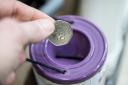 A coin is dropped into a charity collection container in London (PA)