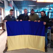 SUPPORT: Kai Wier (far left) in Polish airport holding a Ukrainian flag.